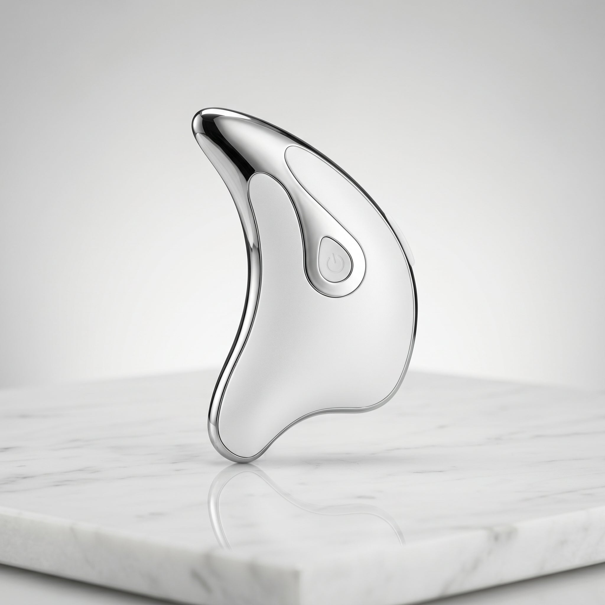 Silver Gua Sha tool on a marble surface with a light gray background
